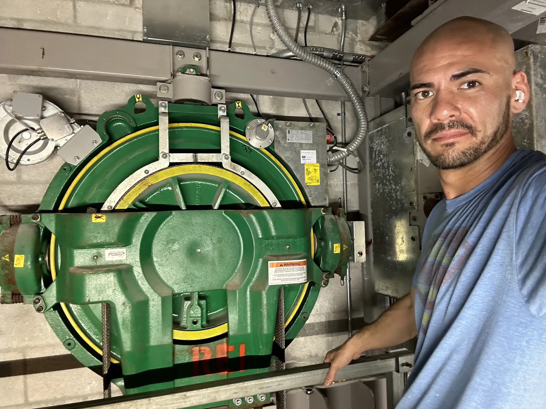 Worker beside green elevator machinery